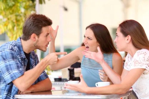 Две женщины и мужчина сидят за столом и спорят